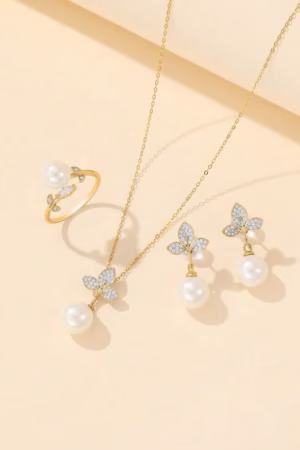 A beautiful gold-tone jewelry set with a butterfly design, featuring a pearl necklace, matching earrings, and a ring.