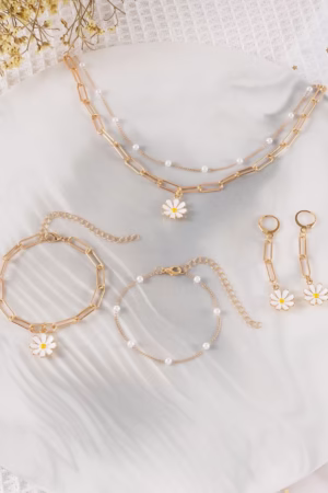 A gold-tone daisy charm jewelry set including necklaces, bracelets, and earrings with pearl accents.