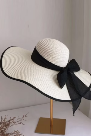 Elegant wide-brim white straw hat with a black ribbon bow, perfect for summer outings and beachwear.