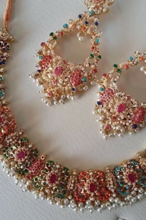 A gold-tone choker necklace with colorful gemstones and pearl accents, paired with matching earrings.