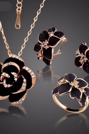 A black rose-themed jewelry set including a necklace, earrings, and ring with gold-tone details and crystal accents.