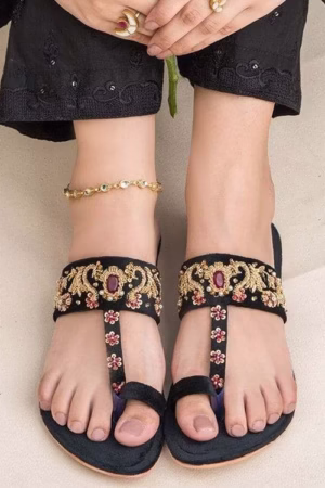 A luxurious handcrafted Kolhapuri sandal in black velvet, featuring intricate golden embellishments, double-padded sole, and a non-slip base for ultimate comfort and style.