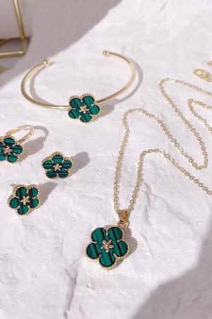 Green floral jewelry set with necklace, earrings, ring, and bracelet on a white textured background