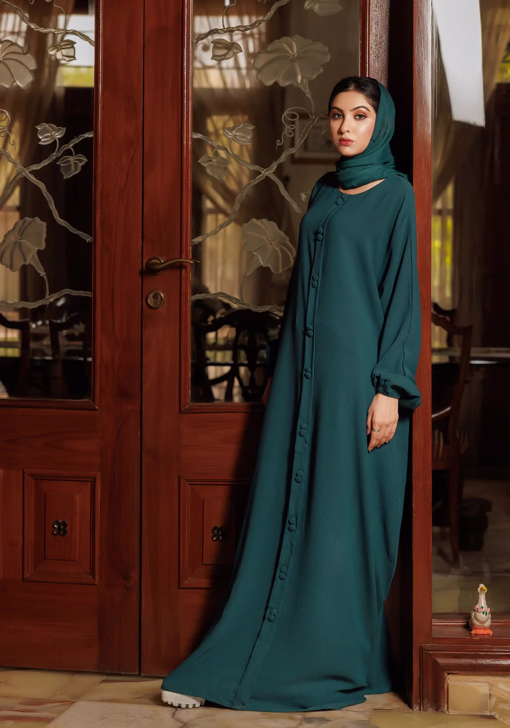 Green Fancy Button Abaya: Graceful Design with Intricate Button Details A Green Fancy Button Abaya displayed on a mannequin, highlighting its elegant tailoring and ornate button details.